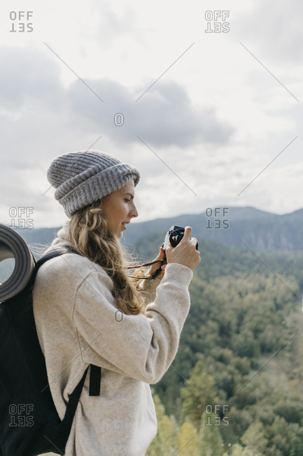 Beautiful young woman with backpack and film camera takes pictures.