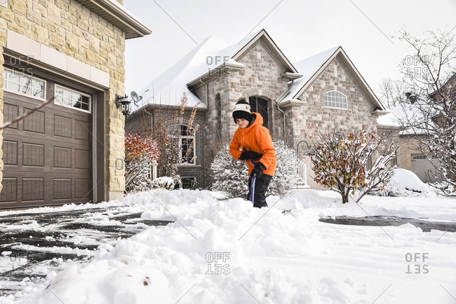 Boy shoveling snow off of a driveway after a winter storm