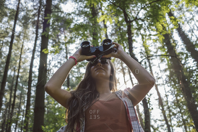 Woman looking with binoculars in the forest
