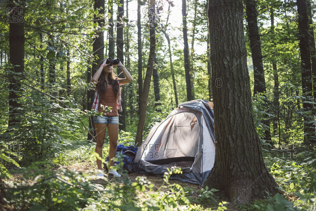 Woman looking with binoculars in the forest