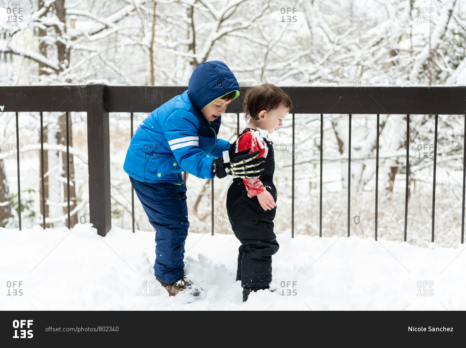 Two boys playing in the snow on a snowy deck