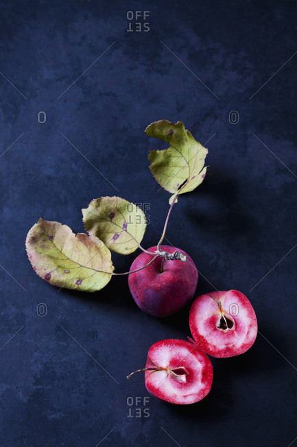 Sliced and whole red-fleshed apples on dark ground