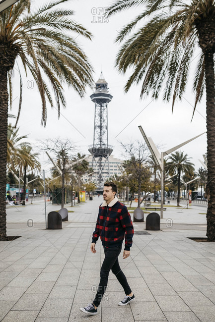 Spain- Barcelona- Young man with casual clothes walking on a square