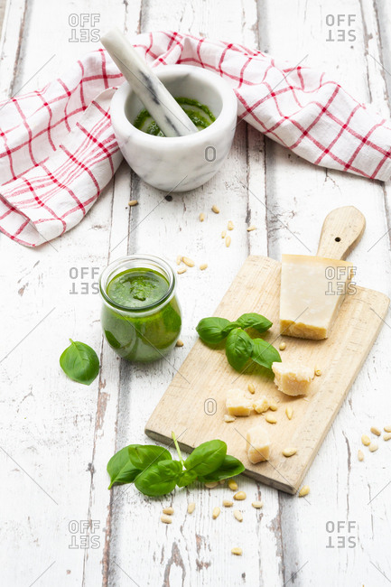 Glass of homemade pesto Genovese- ingredients- mortar and kitchen towel