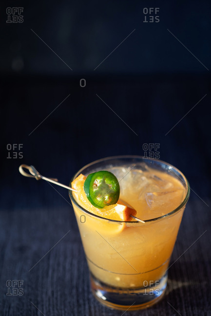 Cocktail garnished with orange and jalapeno