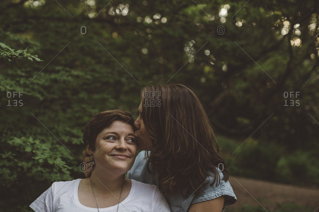 Lesbian couple kissing in forest