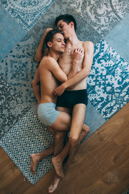 Passionate sexual naked gay couple in an intimate moment lying down in a rug at home