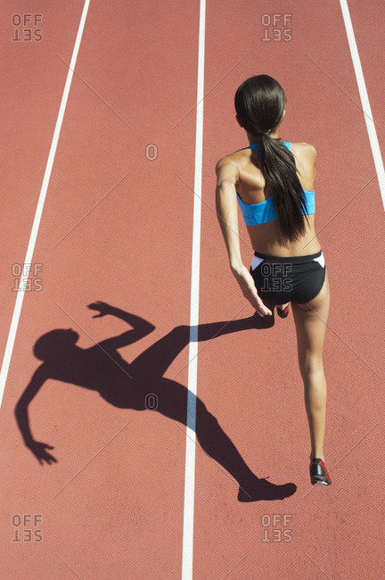 Female athlete running on track, focus on shadow