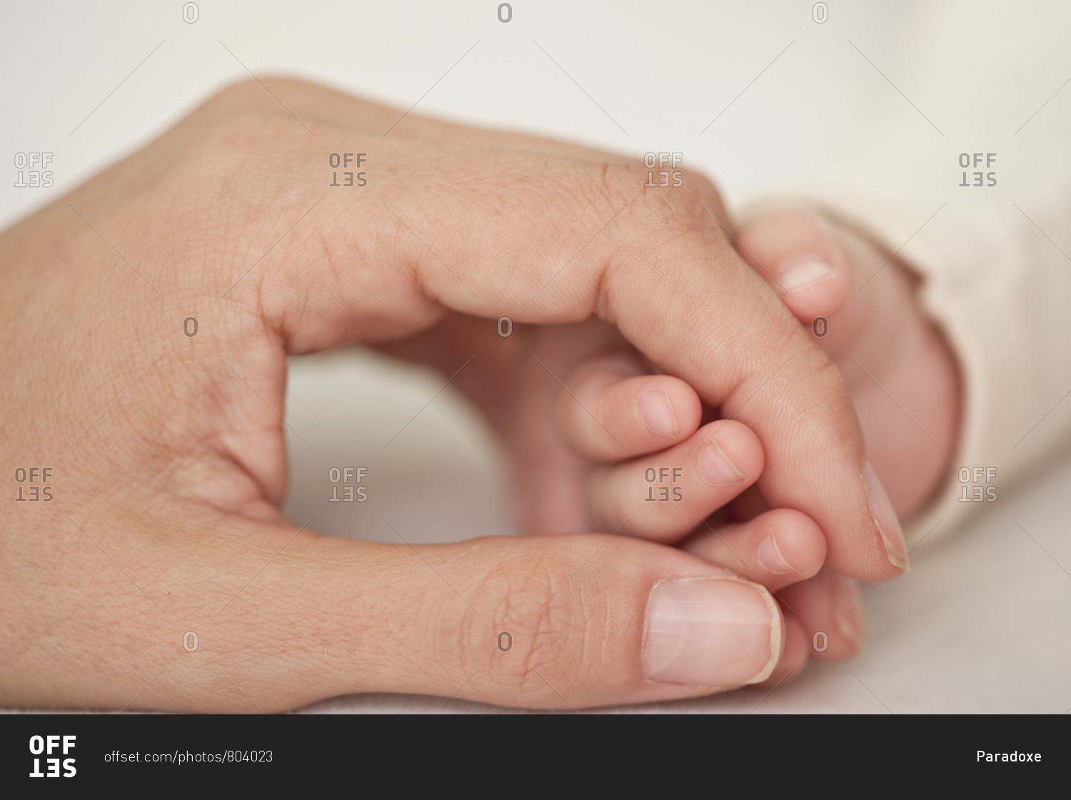 Baby and mother holding hands, cropped, close-up