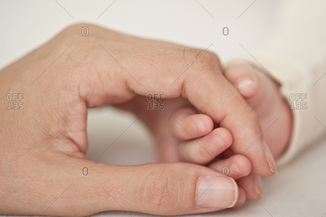 Baby and mother holding hands, cropped, close-up