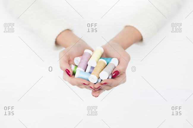 Hands of woman holding spools of cotton