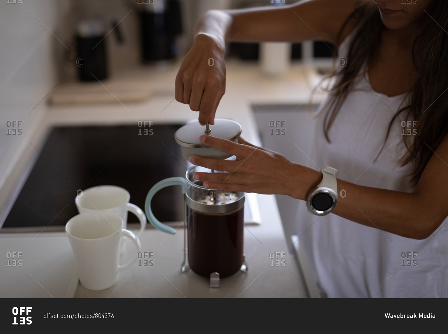 Mid section of mixed-race woman making coffee in coffee maker standing in the kitchen