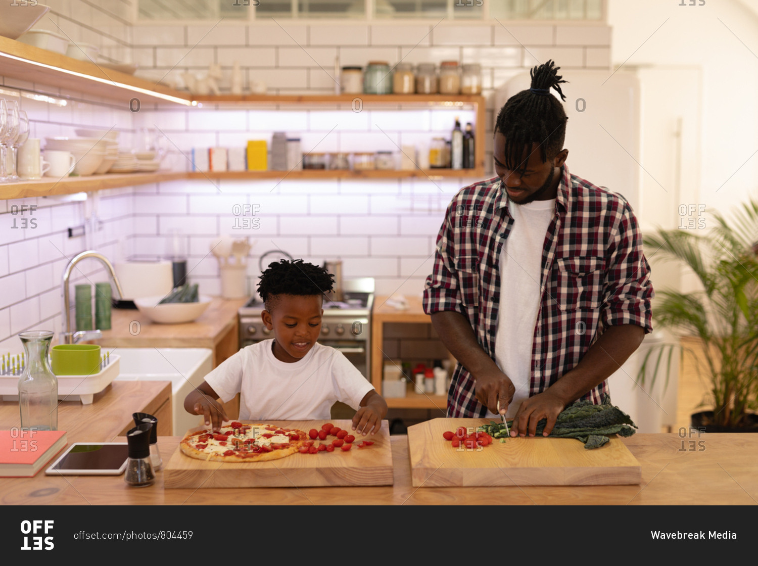 Font view of handsome African-American father and son cooking together in kitchen at home