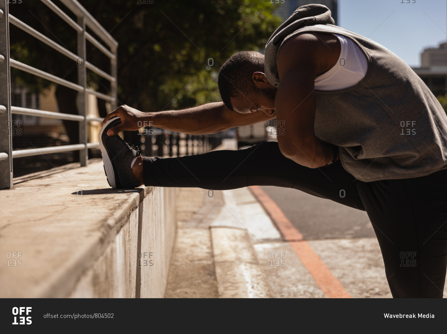 Side view of young African-American fit man doing exercise on the street