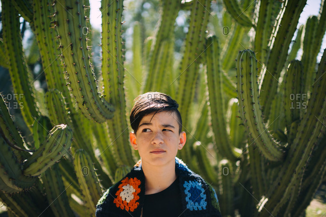 Boy standing by cactus plant making silly face
