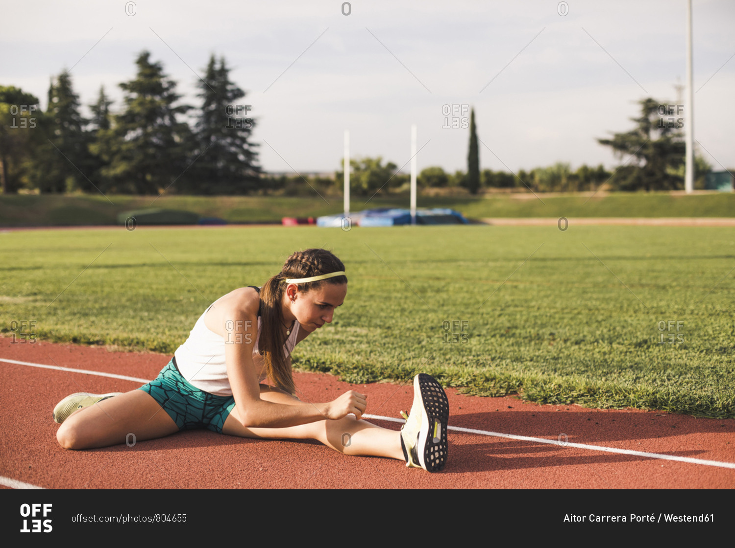 Female athlete doing warm-up exercises on tartan track
