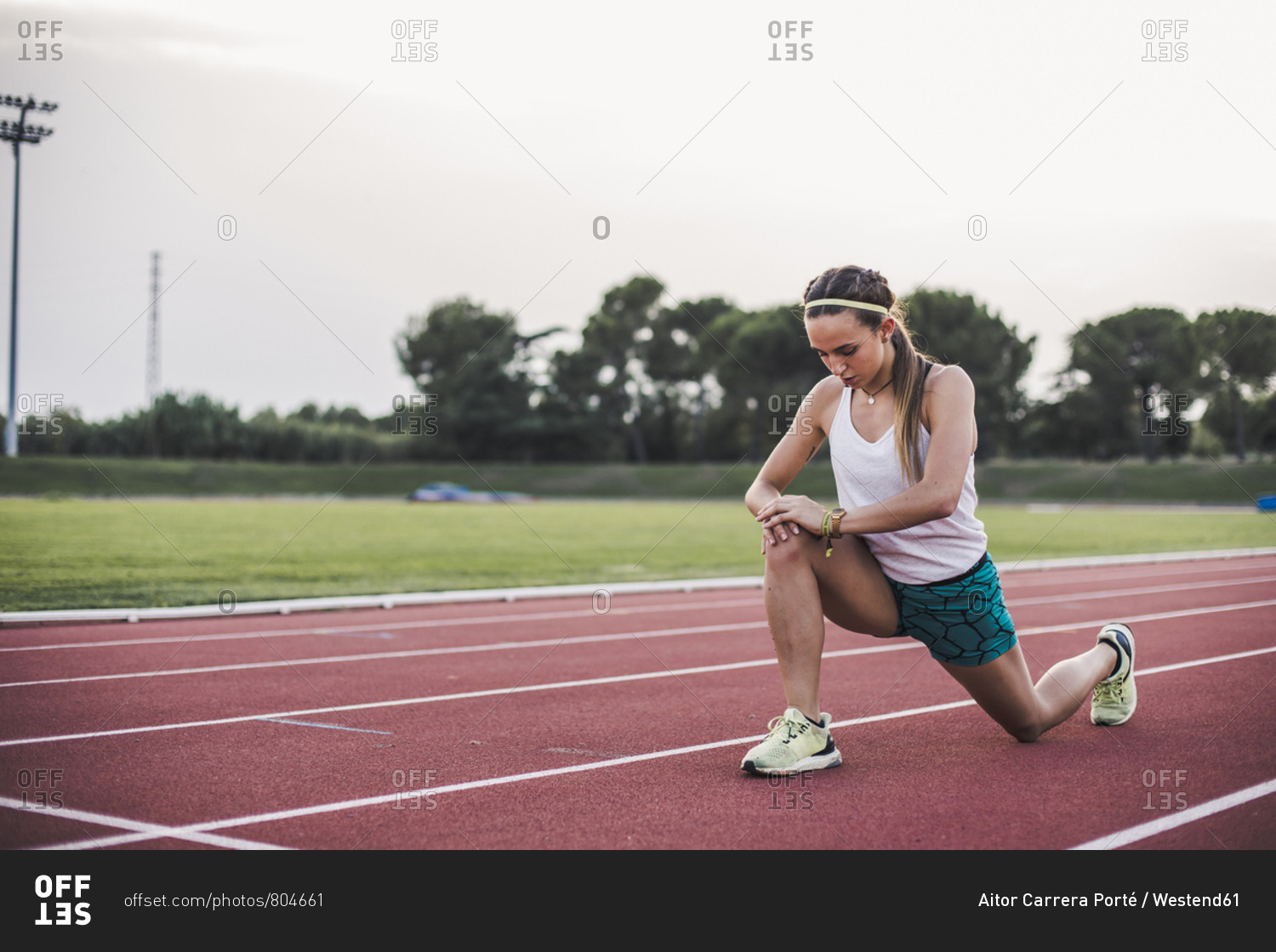 Female athlete doing warm-up exercises on tartan track