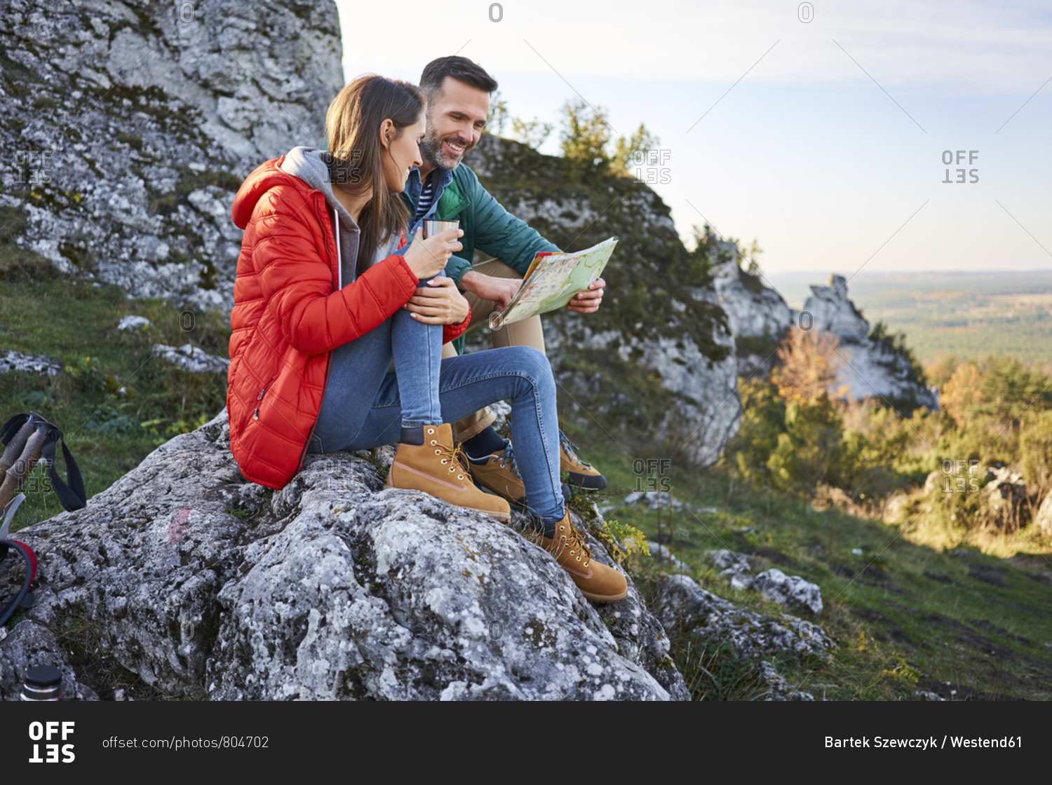 Happy couple on a hiking trip in the mountains taking a break looking at map
