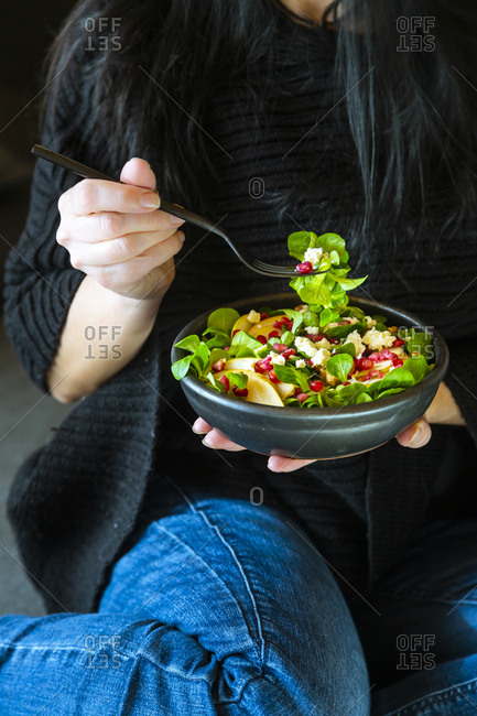 Woman eating mixed salad with lamb's lettuce- feta- pear- pomegranate seed and walnuts