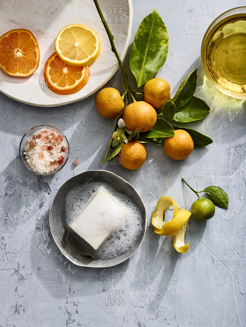 Homeopathic soap on a plate with lemon, lime and oranges near a dish of salt.