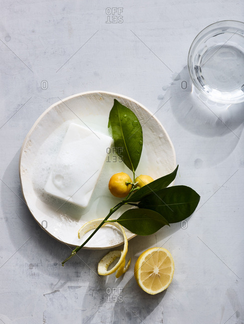 Homeopathic soap on a plate with lemon near a glass of water.