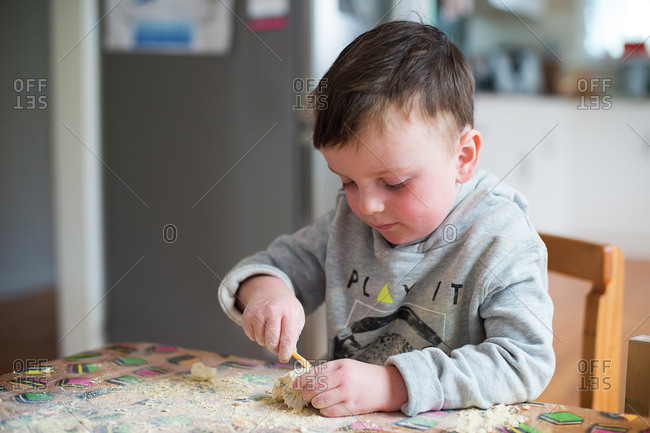 Boy digs toy dinosaur fossil out of rock