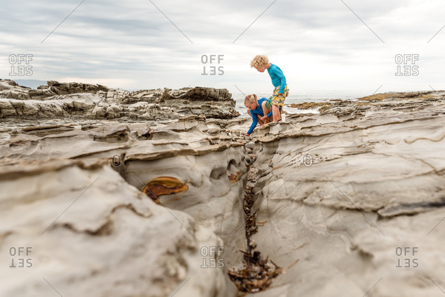 Siblings exploring rocky terrain by the bay