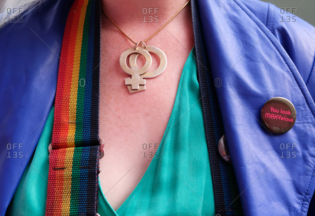 Close-up of a woman wearing a rainbow camera strap and gender politics related accessories