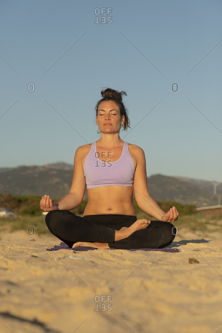 Woman meditating on the beach in the evening