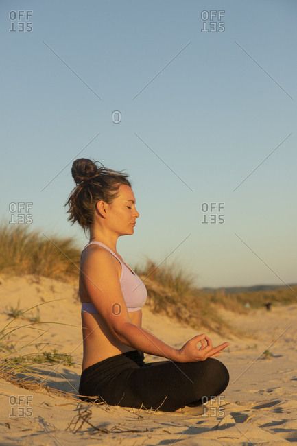 Woman meditating on the beach in the evening