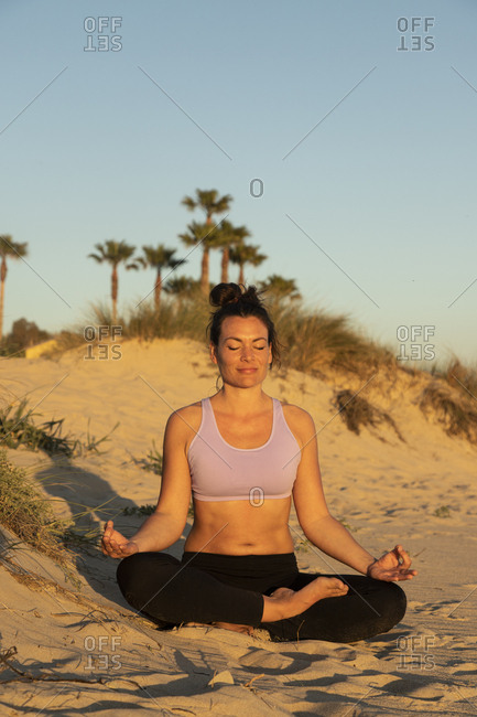 Woman meditating on the beach in the evening