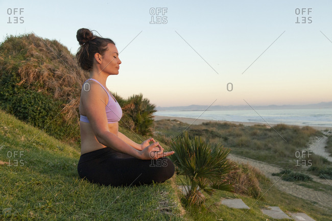 Woman meditating on the beach in the evening