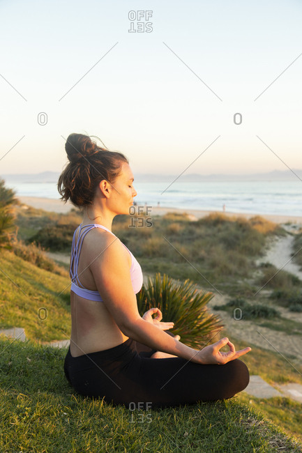 Woman meditating on the beach in the evening