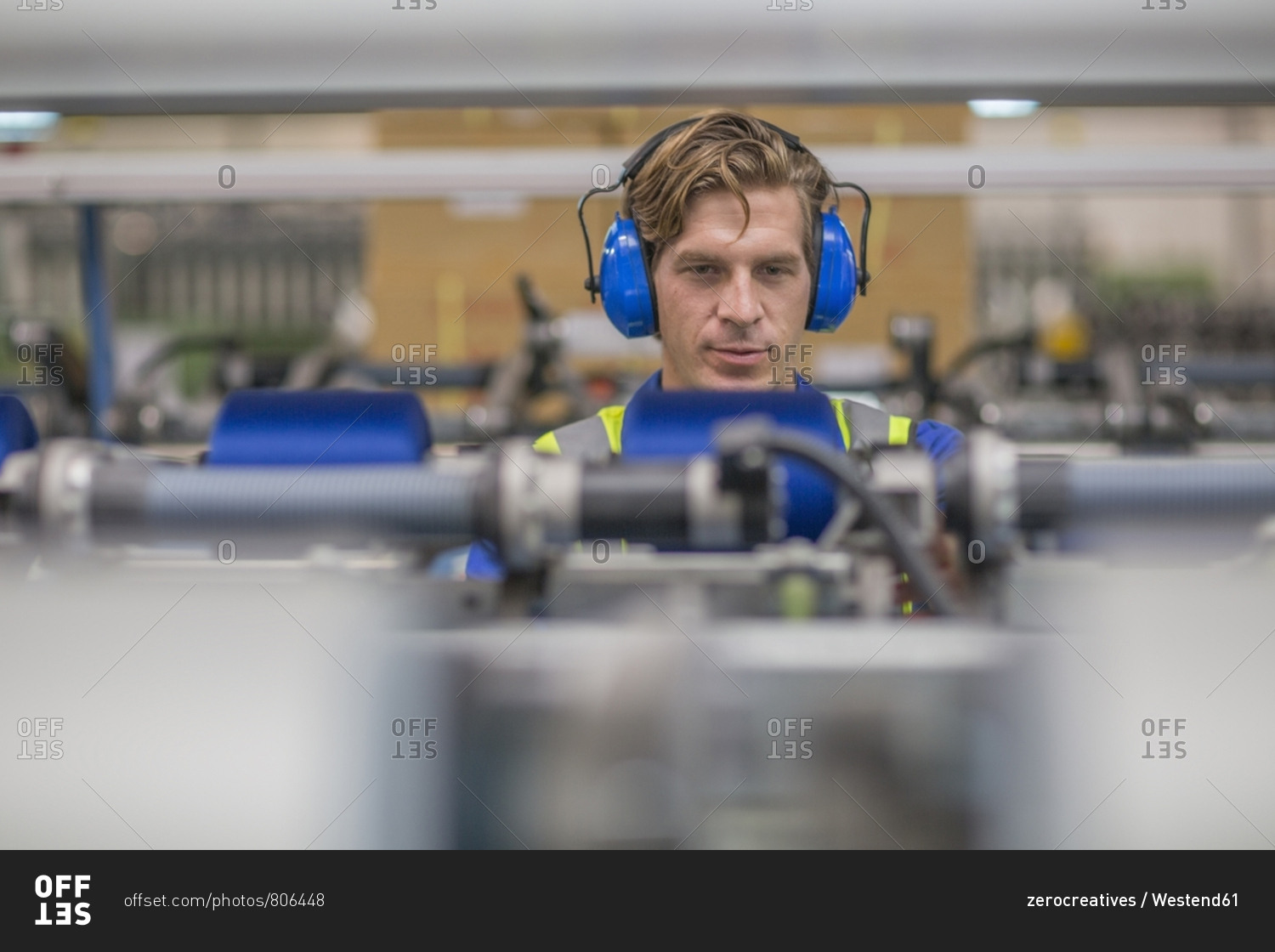 Man wearing ear defenders operating machine in factory