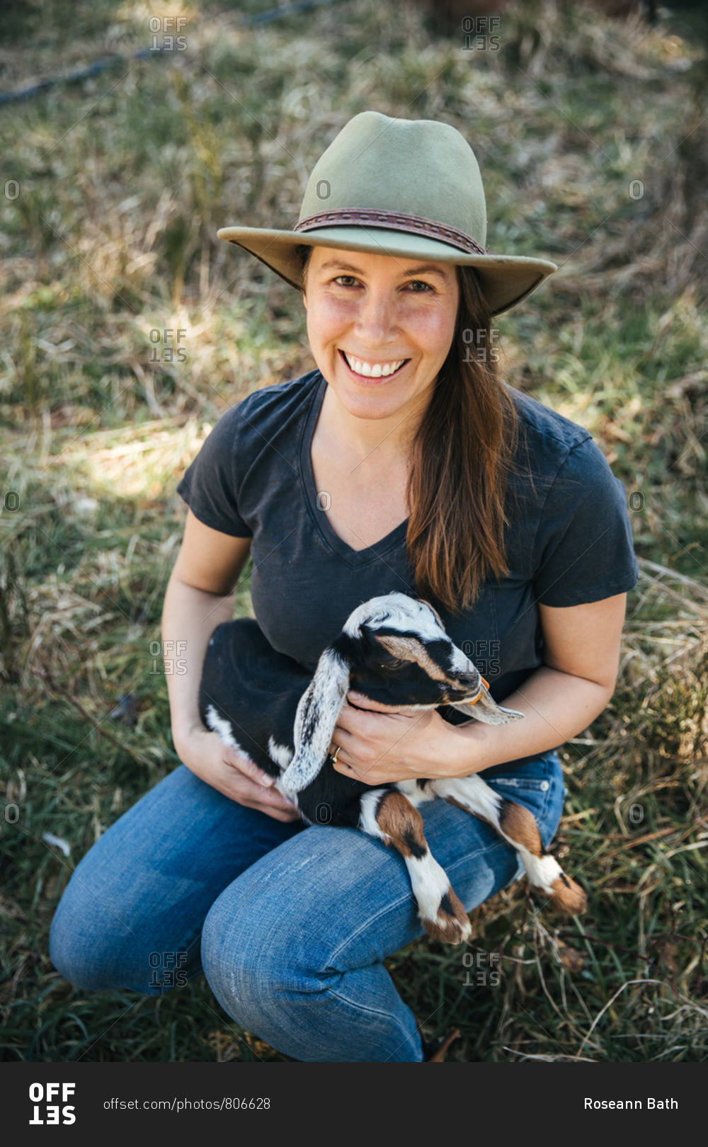 Woman in a hat holding a baby goat.