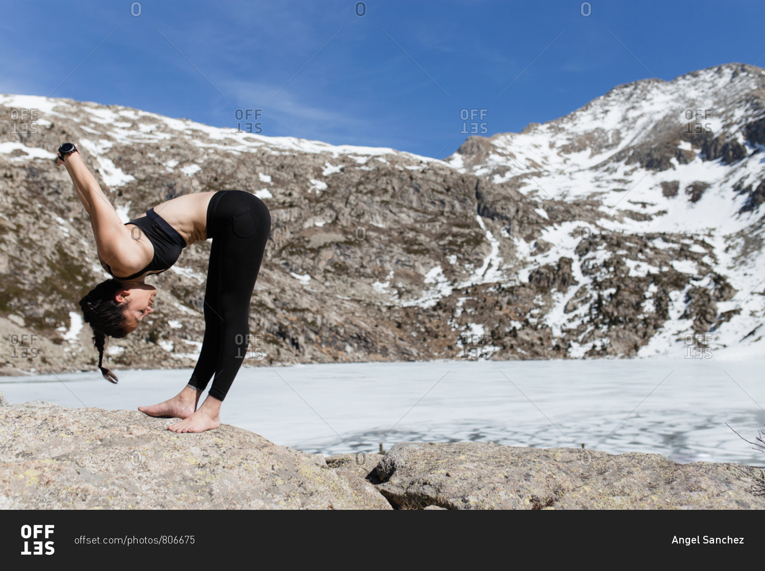 Young hiker woman doing yoga in the nature in a sunny day mountains and frozen lake background