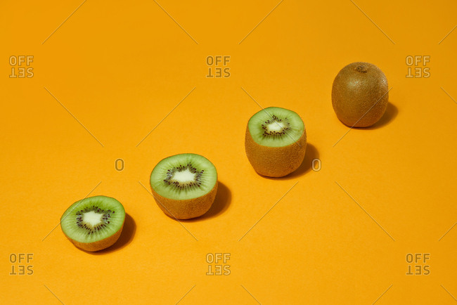 Fresh whole and cut kiwi  on yellow background. Development Concept.