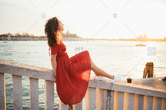 Young woman in red dress, eyes closed, breathing,  enjoying sunset