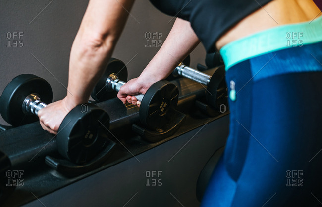 Woman taking dumbbell in gym