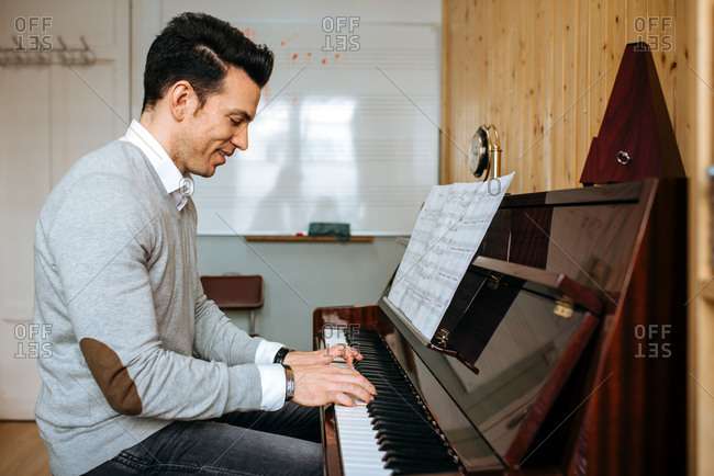 Handsome man playing piano during rehearsal in recording studio.