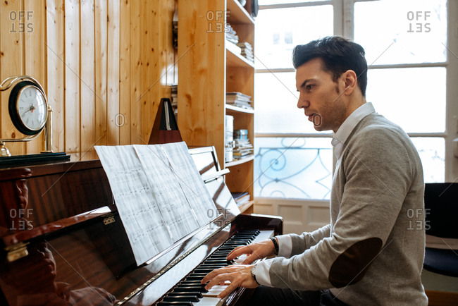 Handsome man playing piano during rehearsal in recording studio.