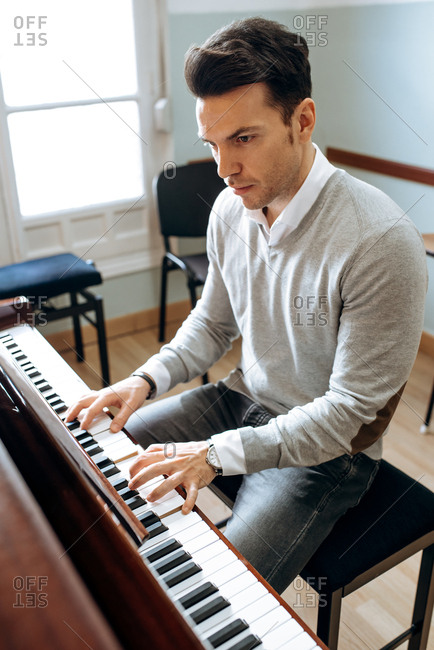 Handsome man playing piano during rehearsal in recording studio.