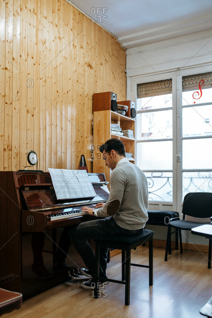 Handsome man playing piano during rehearsal in recording studio.