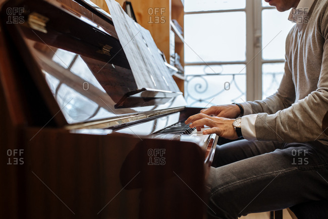 Handsome man playing piano during rehearsal in recording studio.