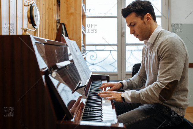Handsome man playing piano during rehearsal in recording studio.
