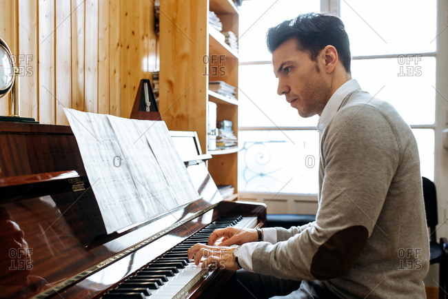 Handsome man playing piano during rehearsal in recording studio.