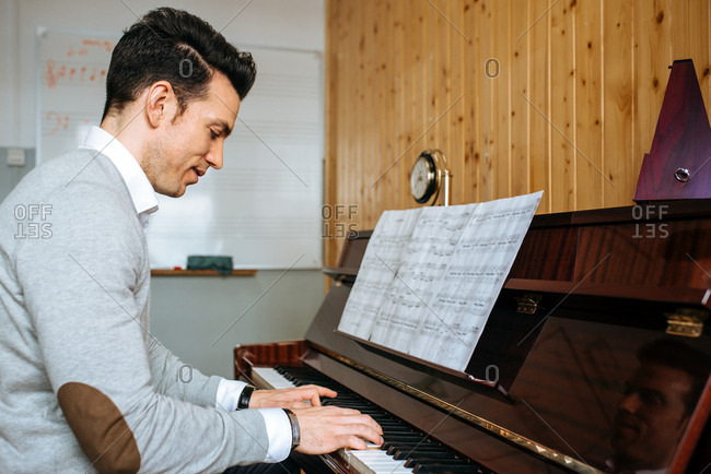Handsome man playing piano during rehearsal in recording studio.