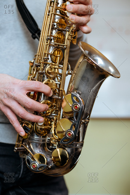 Cropped unrecognizable man playing saxophone in studio