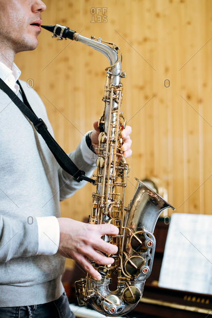 Cropped unrecognizable man playing saxophone in studio