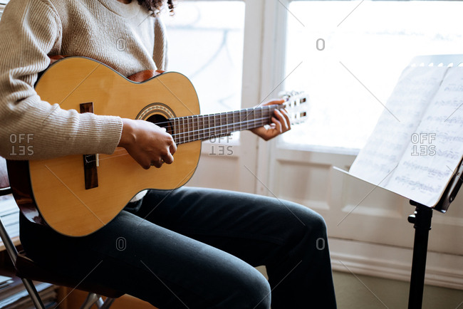 Black woman playing guitar during rehearsal in recording studio.